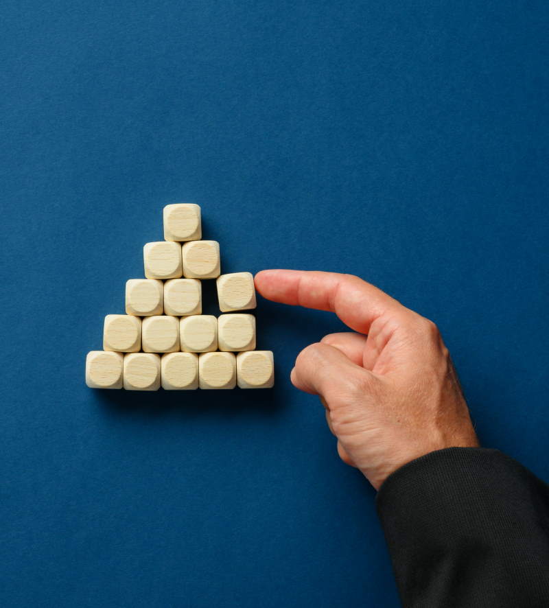 Hånd der sætter en brik på plads, så brikkerne danner en pyramideform